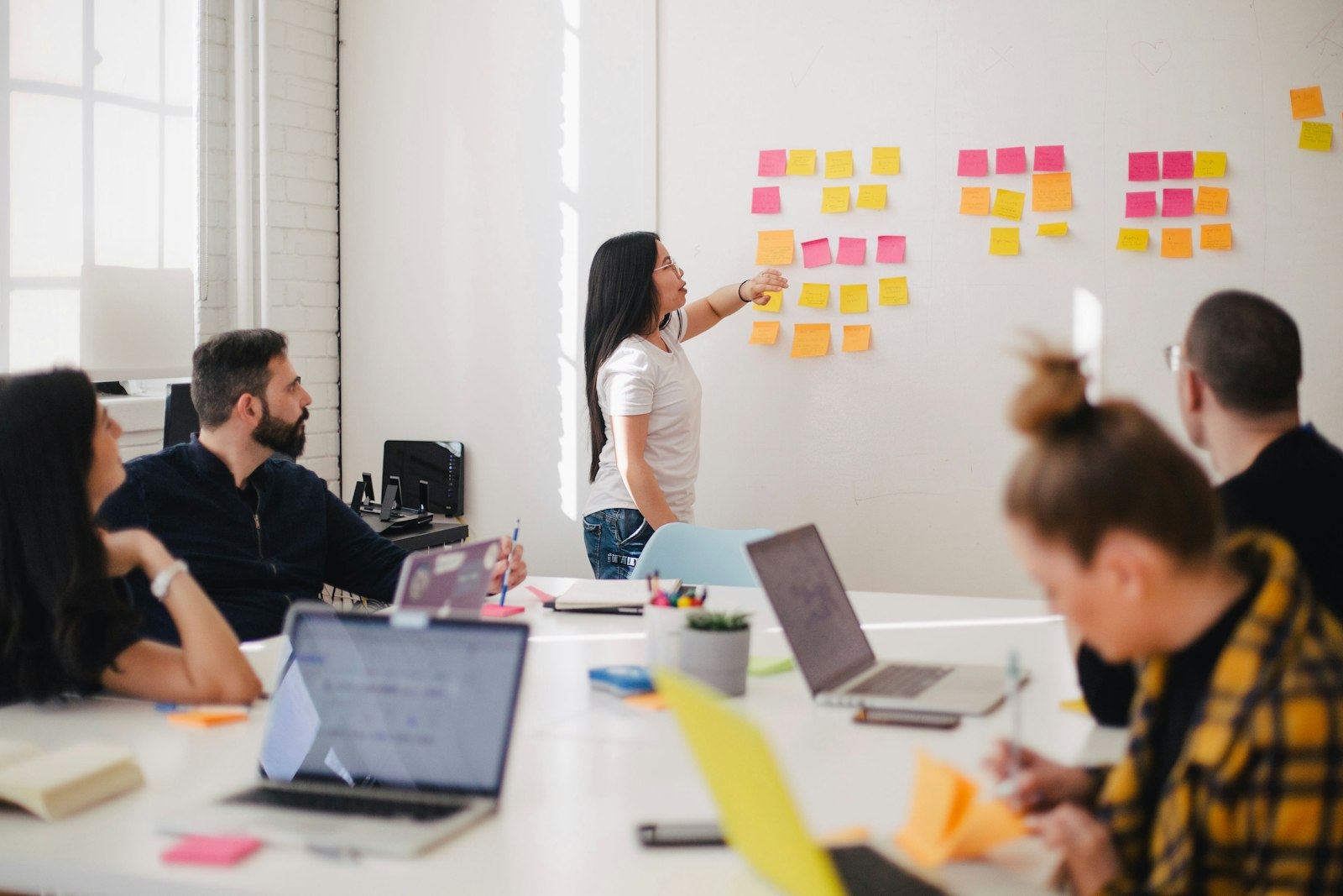 A team reviewing colour-coded notes arranged on a wall during a working session