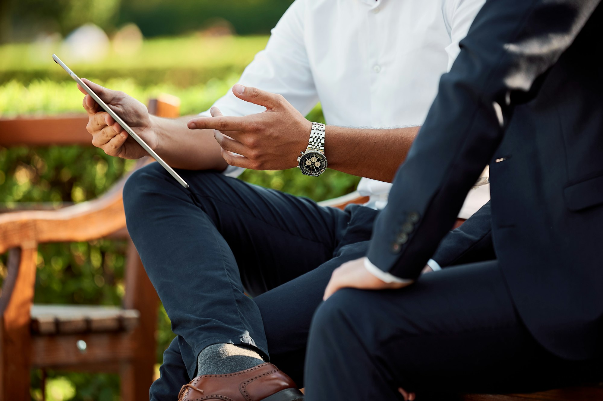 Two colleagues seated on a bench, one holding a tablet while the other points to the screen